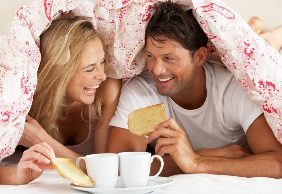 un homme et une femme prennent le petit dejeuner dans leur lit