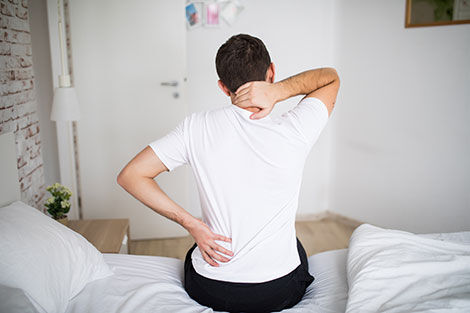 un homme qui à mal dormi sur son lit